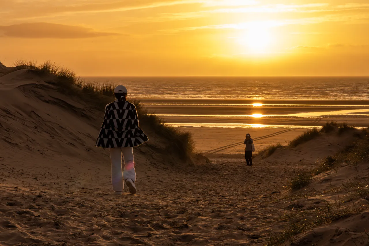 A man and a woman walking down a beach